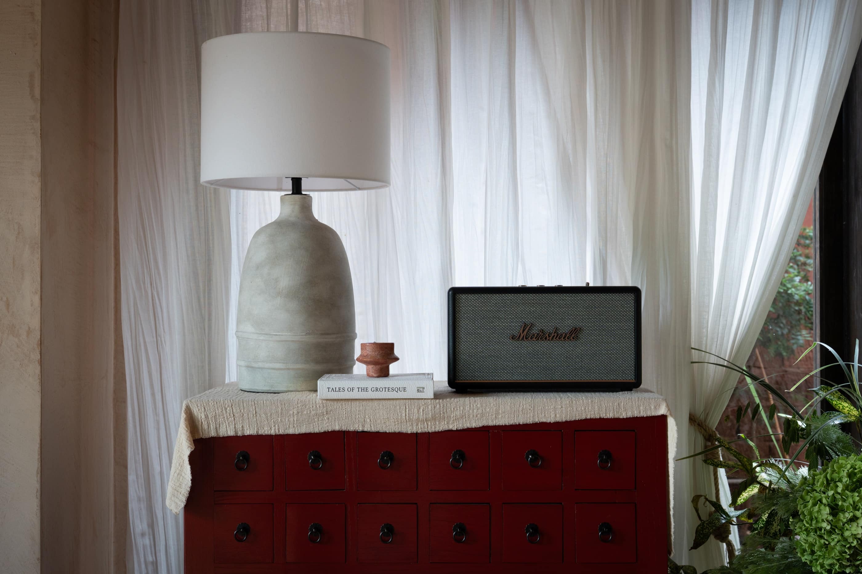 A quiet interior with a red cabinet, lamp, and speaker