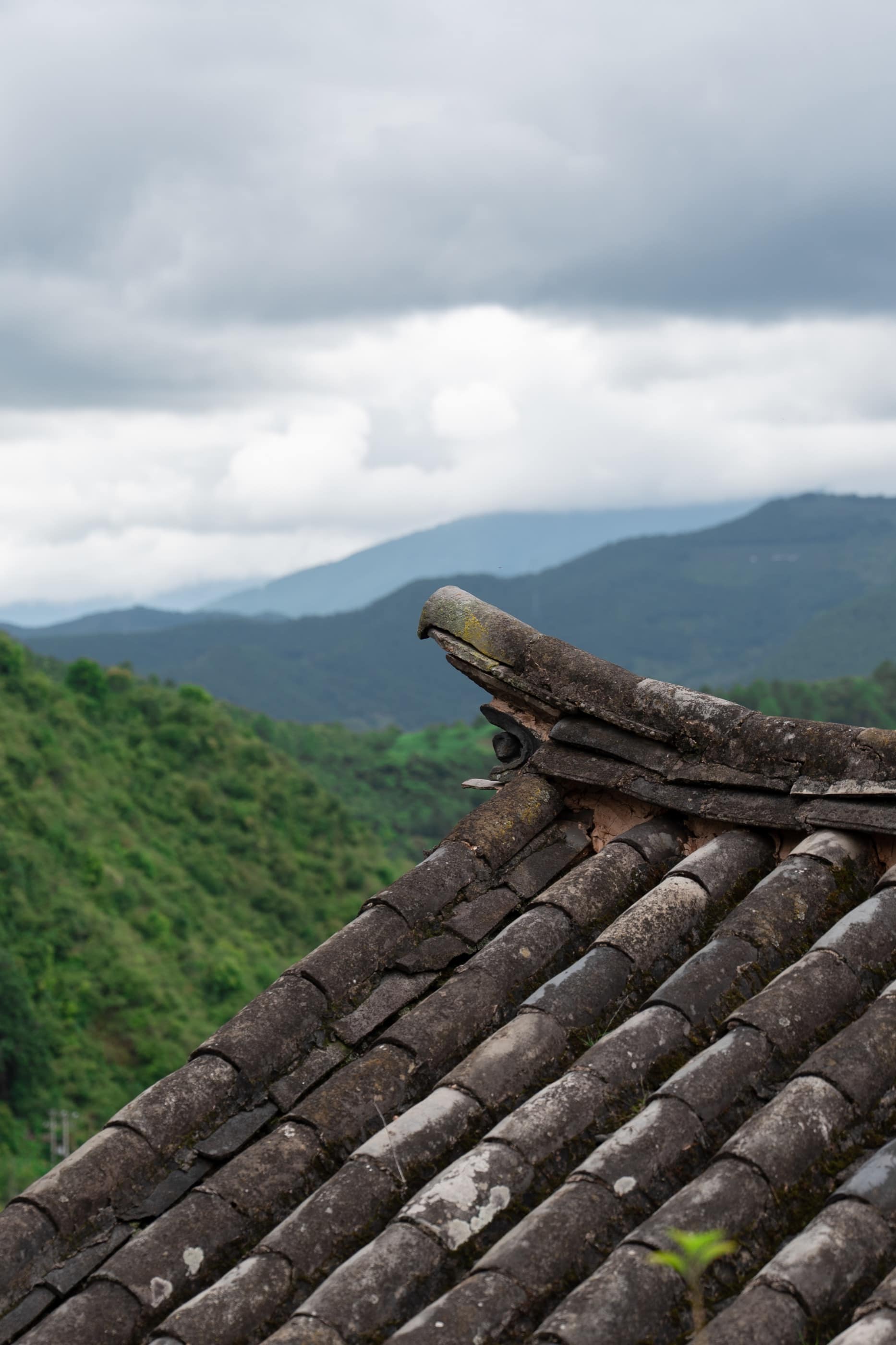 Weathered roof tiles against clouded mountains