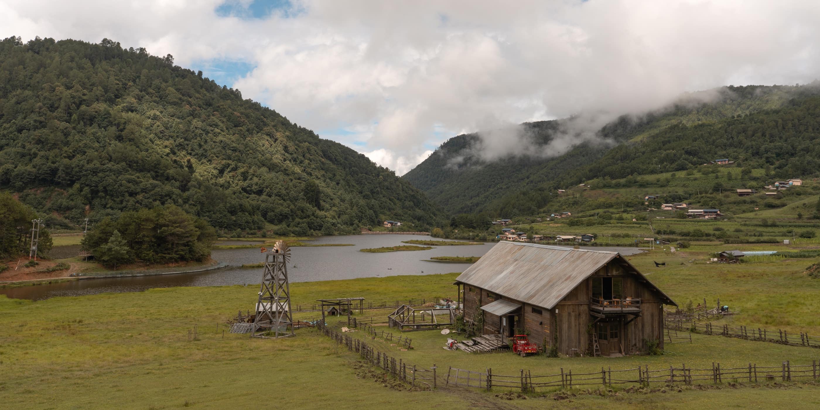 A small wooden house beside a lake and mountain meadow