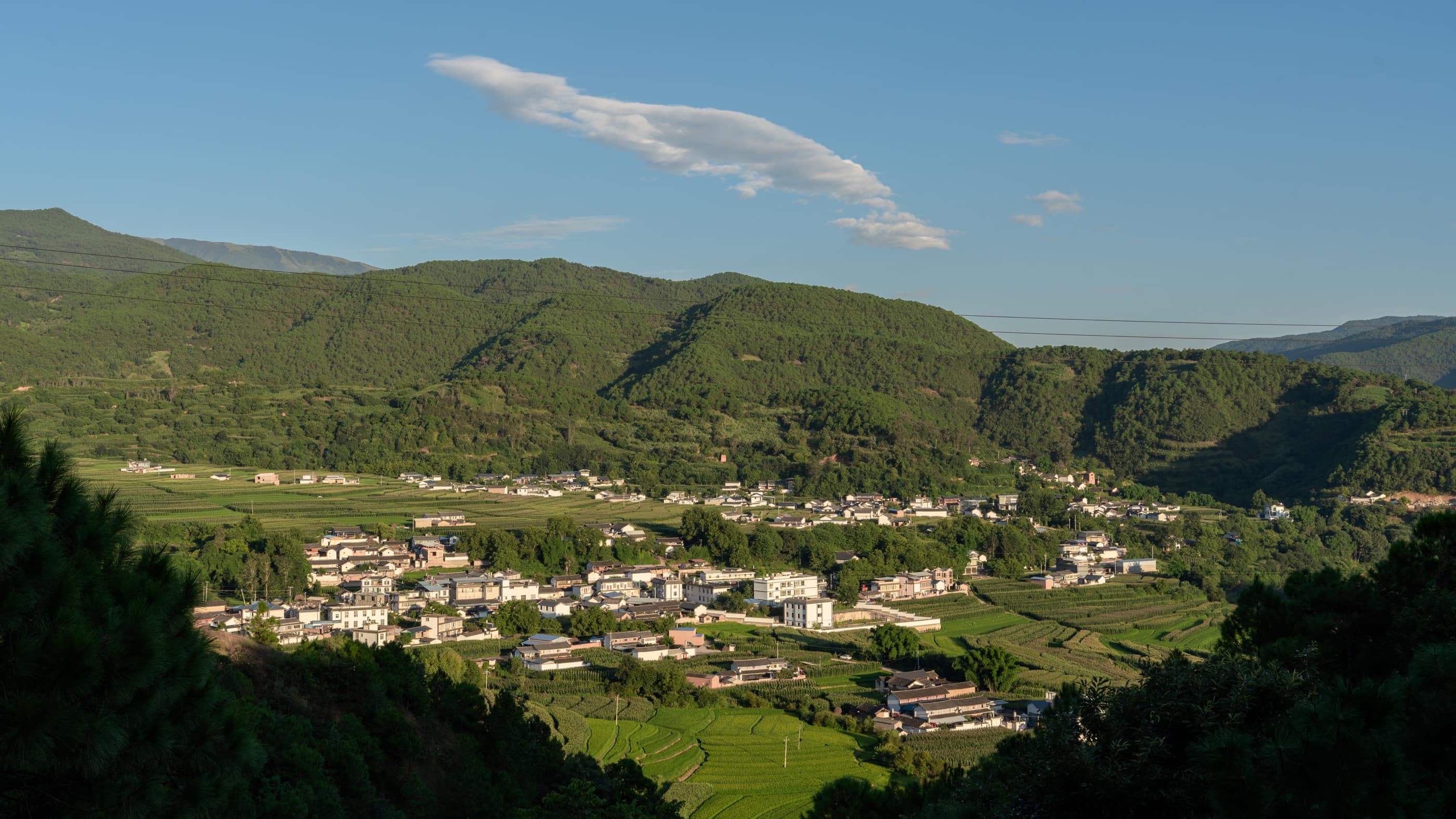 A village spread across a sunlit green valley
