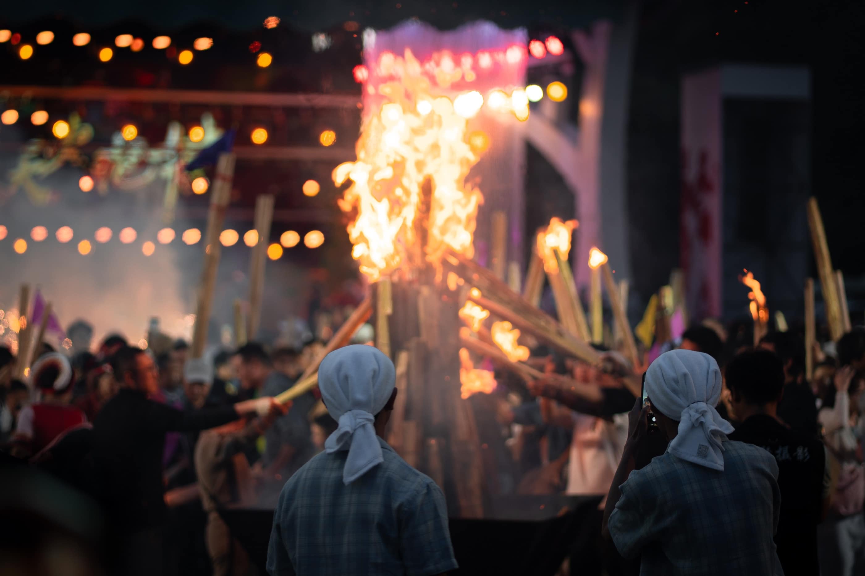 A crowd gathering around rising fire at night