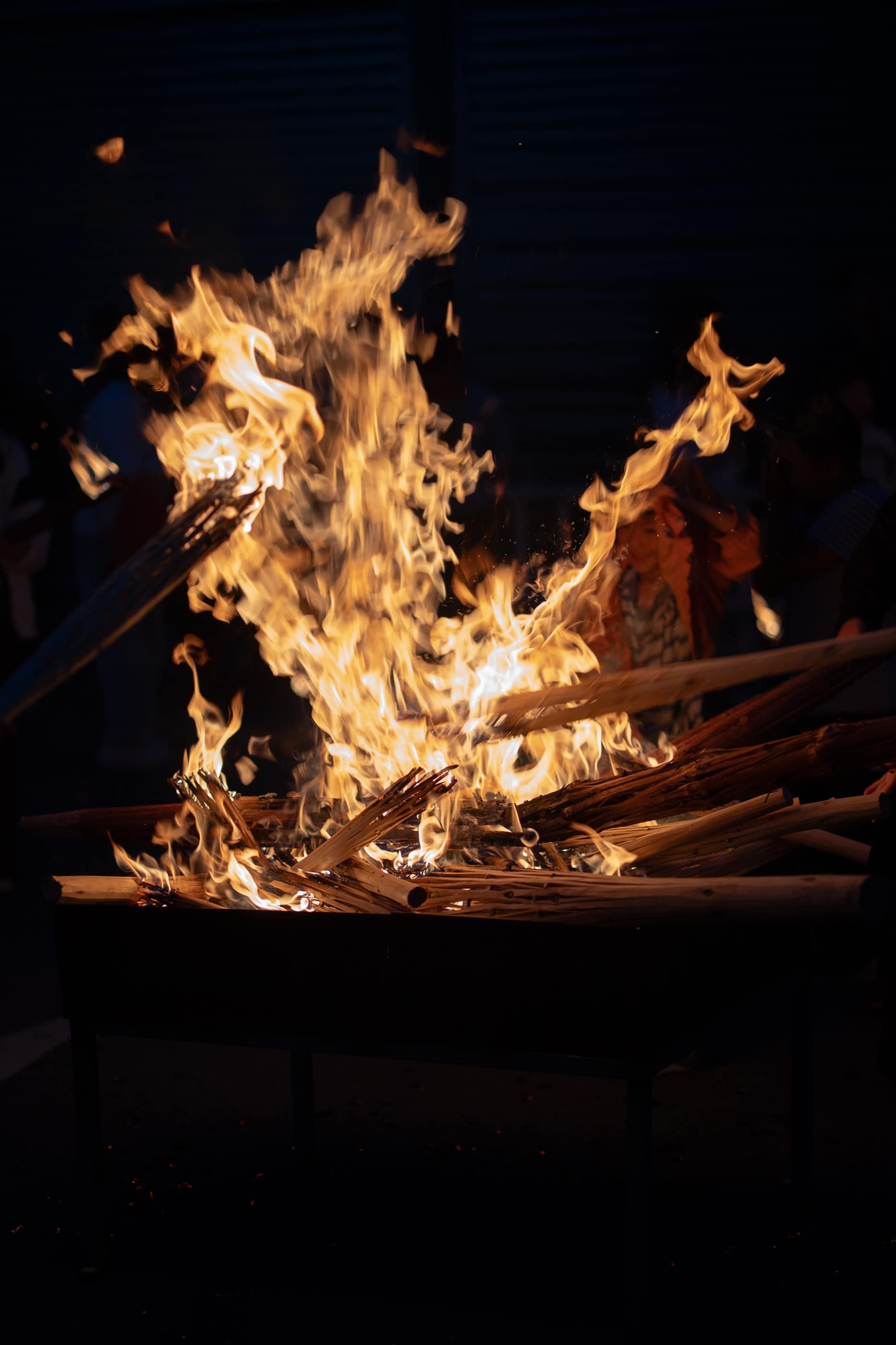 Flames curling around stacked wood in darkness
