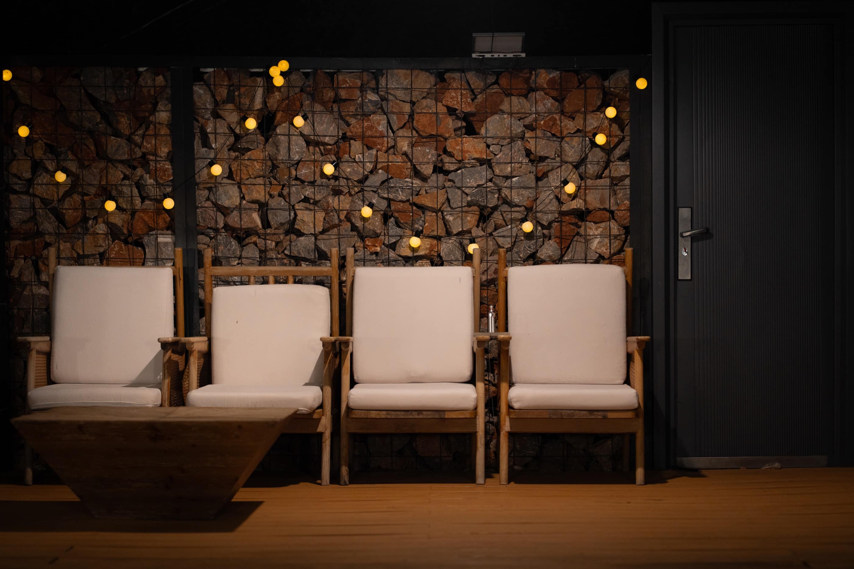 Four empty chairs against a stone wall at night
